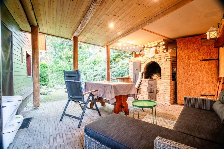 Pergola s jídelním stolem, lehátkem a lesem v pozadí