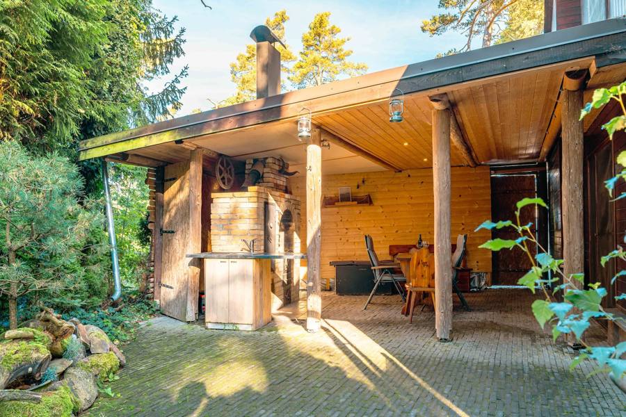 Pergola s krbem a komínem mezi stromy